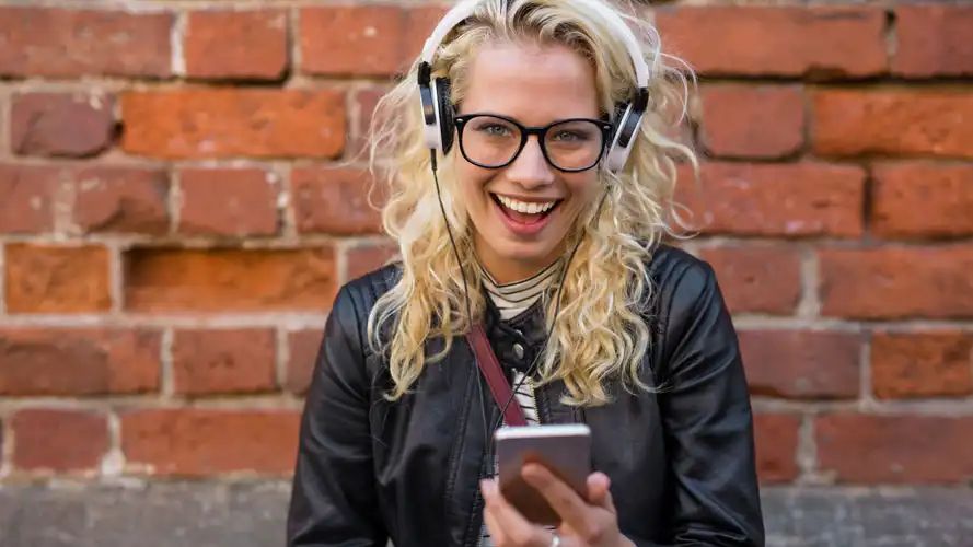 Smiling woman listening to audio book outisde